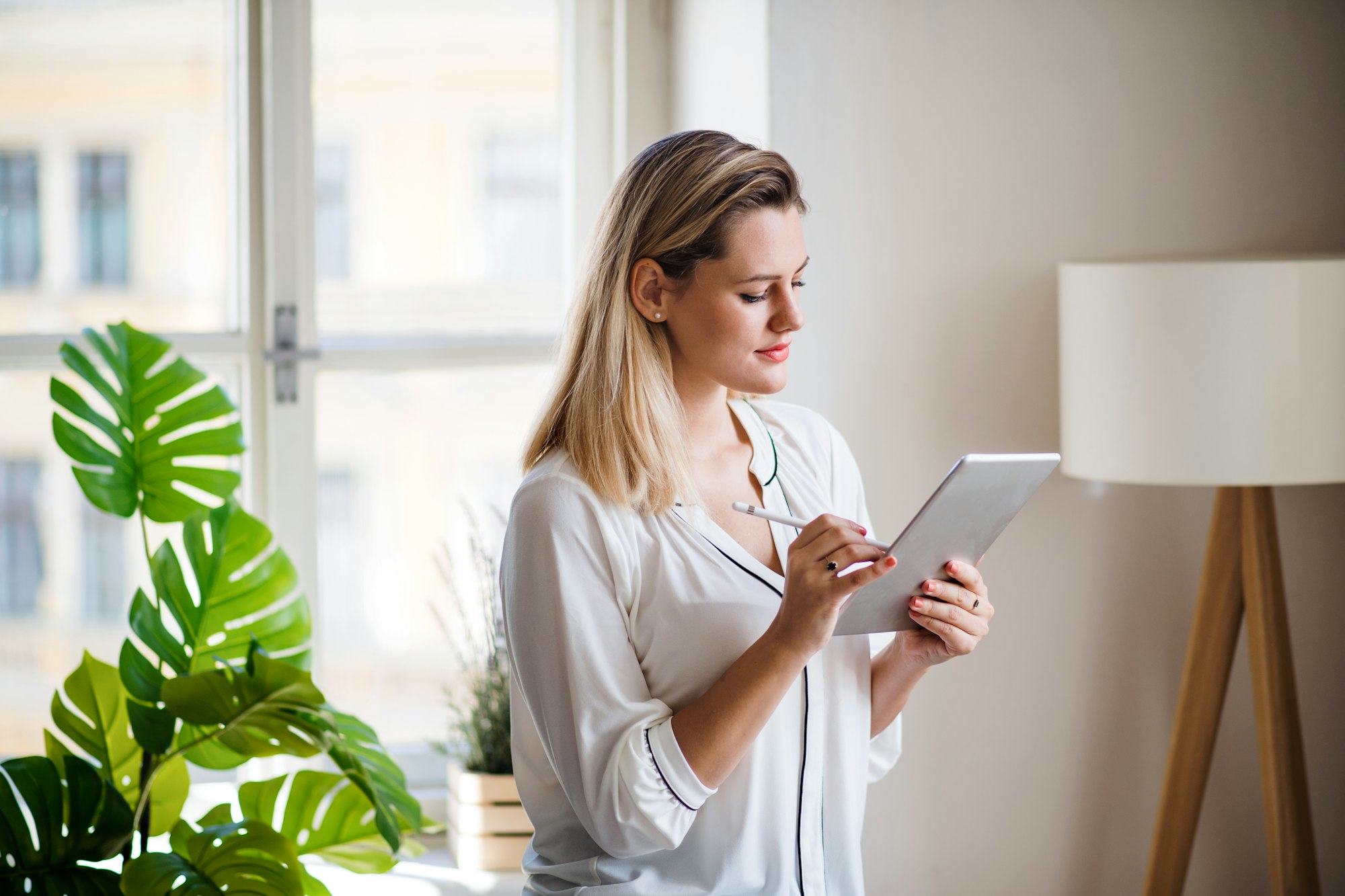 Young woman with tablet indoors in home office, working.